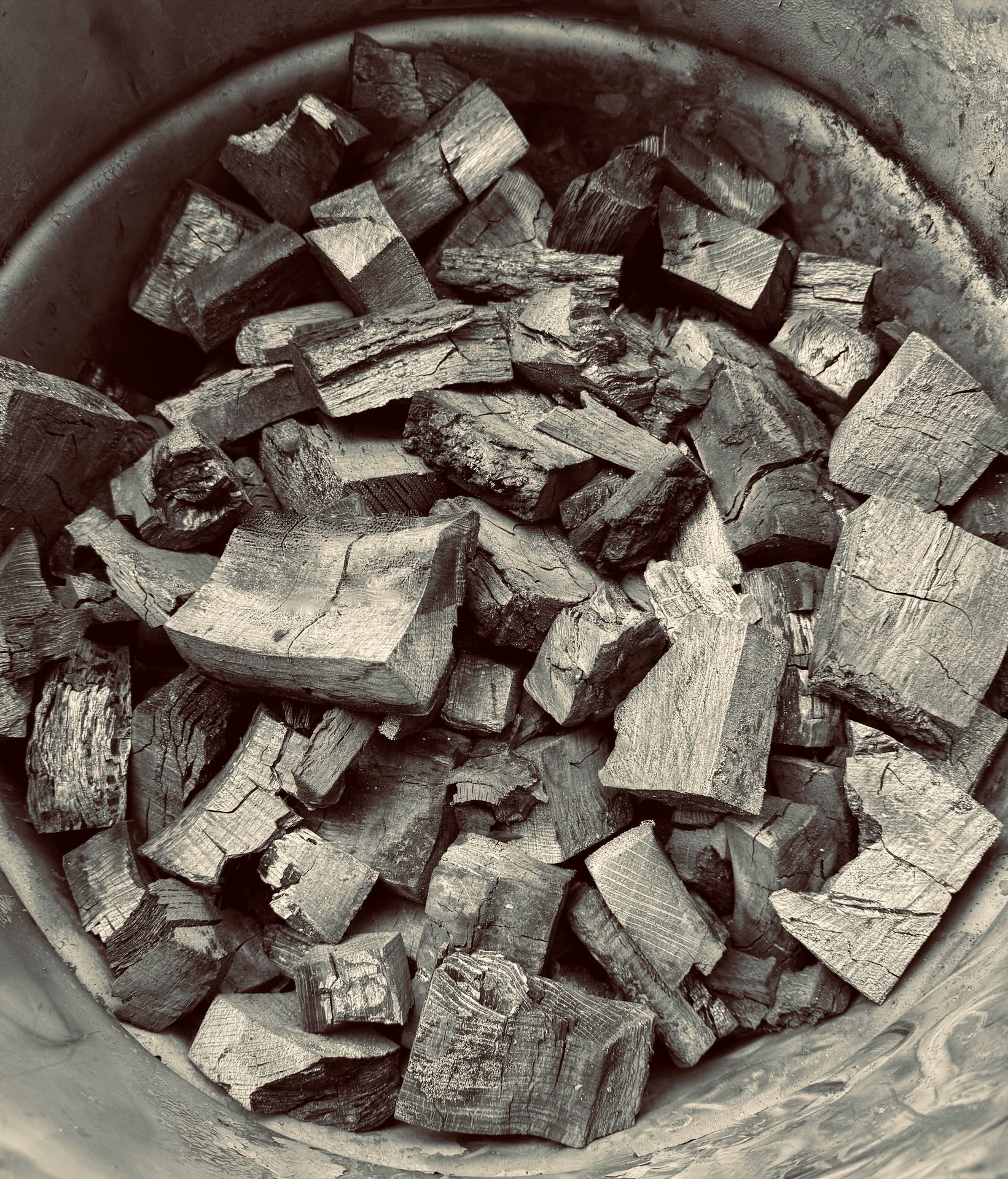 The retort open to glowing embers beside a bin of finished lumpwood charcoal